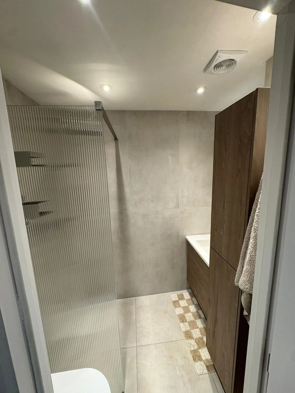 Badkamer met betonlook tegels, houten badkamermeubel en inloopdouche